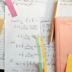 Detailed math notes with handwritten equations and colorful papers, perfect for educational use.